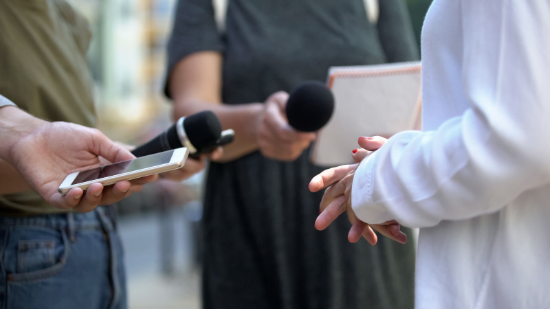 Periodistas con micrófonos, móvil y libreta entrevistan a una persona