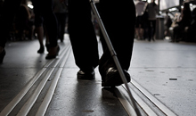 Persona amb discapacitat visual seguint amb un bast unes guies a una estaci. Foto: 85mm.ch (Flickr, CC)