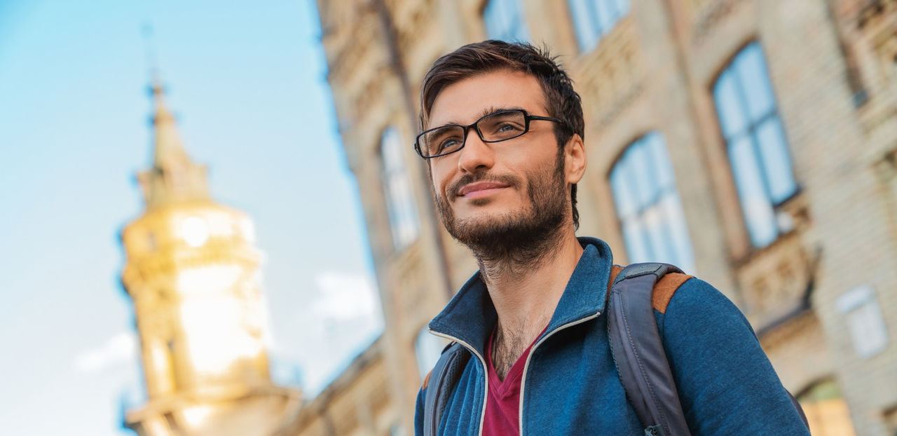 Hombre sonriendo en el exterior de una universidad