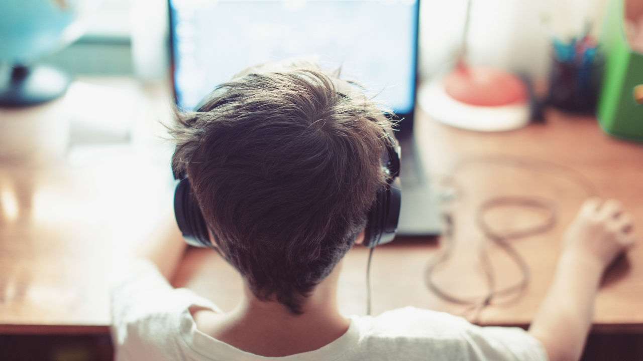 Little dependent gamer kid playing on laptop