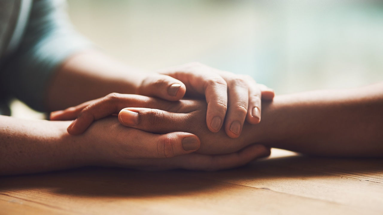 Love, empathy and support with people holding hands in comfort, care or understanding on a wooden table of a home. Prayer, faith or depression with friends closeup for hep, hope or peace for healing Love, empathy and support with people holding hands in comfort, care or understanding on a wooden table of a home. Prayer, faith or depression with friends closeup for hep, hope or peace for healing