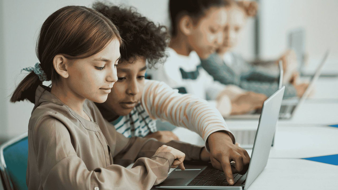 Two girls working with a computer in the classroom