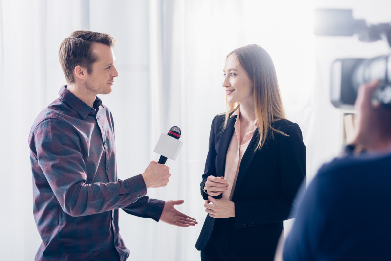 beautiful businesswoman in suit giving interview to handsome journalist in office
