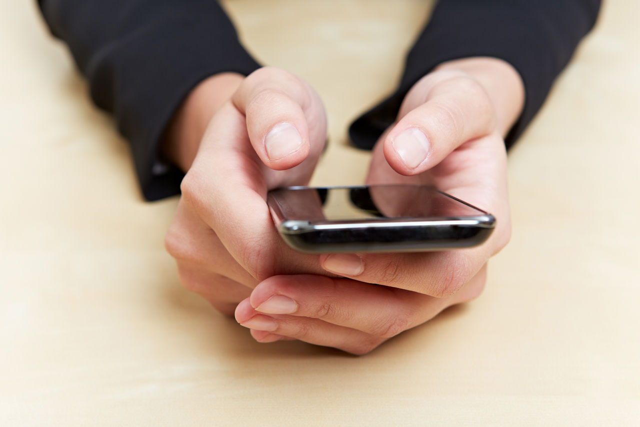 Hände einer Geschäftsfrau am Schreibtisch arbeiten am Smartphone