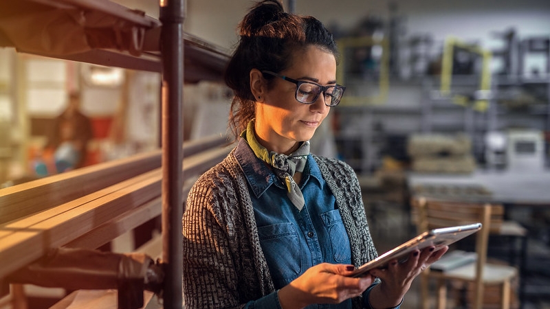 A person looking at a digital tablet inside a workshop or industrial workspace.