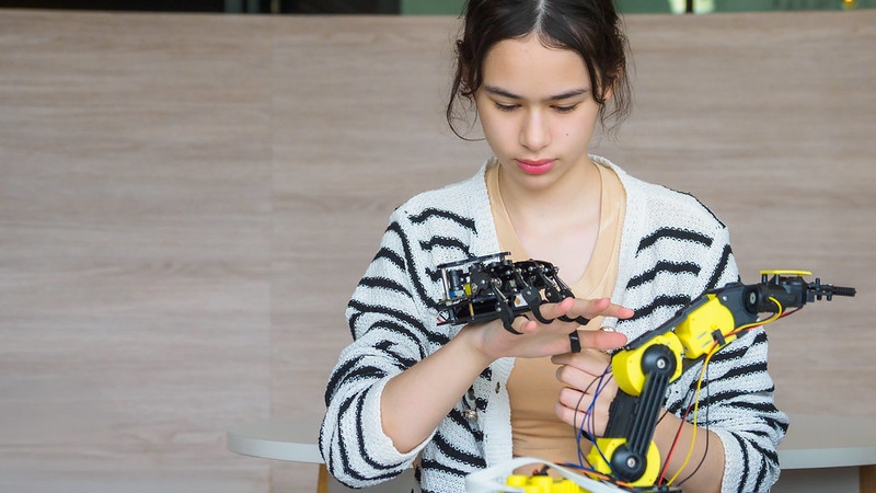 A person carefully examining the mechanics of a robotic arm and hand.