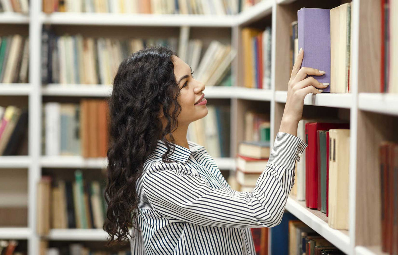  Una chica cogiendo un libro de la biblioteca