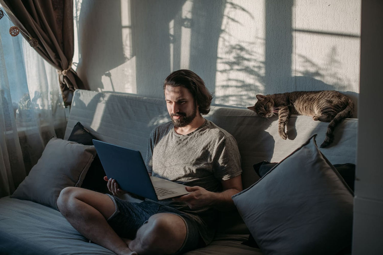 Hombre estudia online desde casa acompañado por su gato