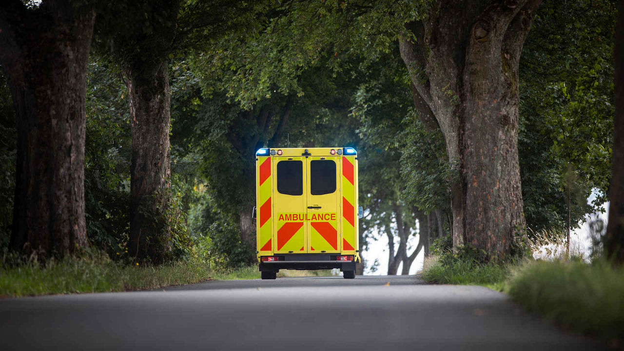 Yellow ambulance car of emergency medical service on country road. Themes rescue, urgency and health care. 