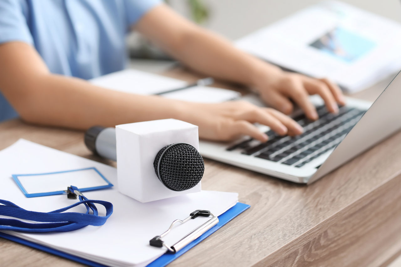 Periodista con portátil y micrófono